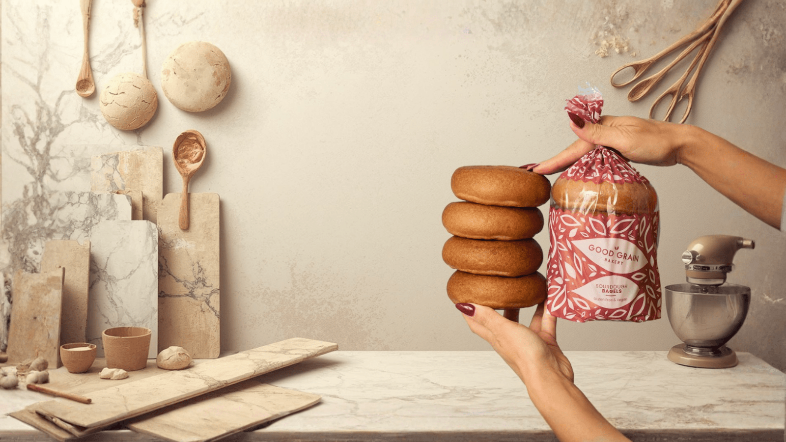 bagels in bag and out of bag being held up by hands against a blue background